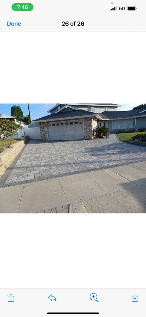 Large gray paver driveway with stone facade garage